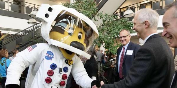 Ralphie mascot in an astronaut suit shaking hands